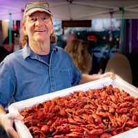 a man holding a tray full of crawfish